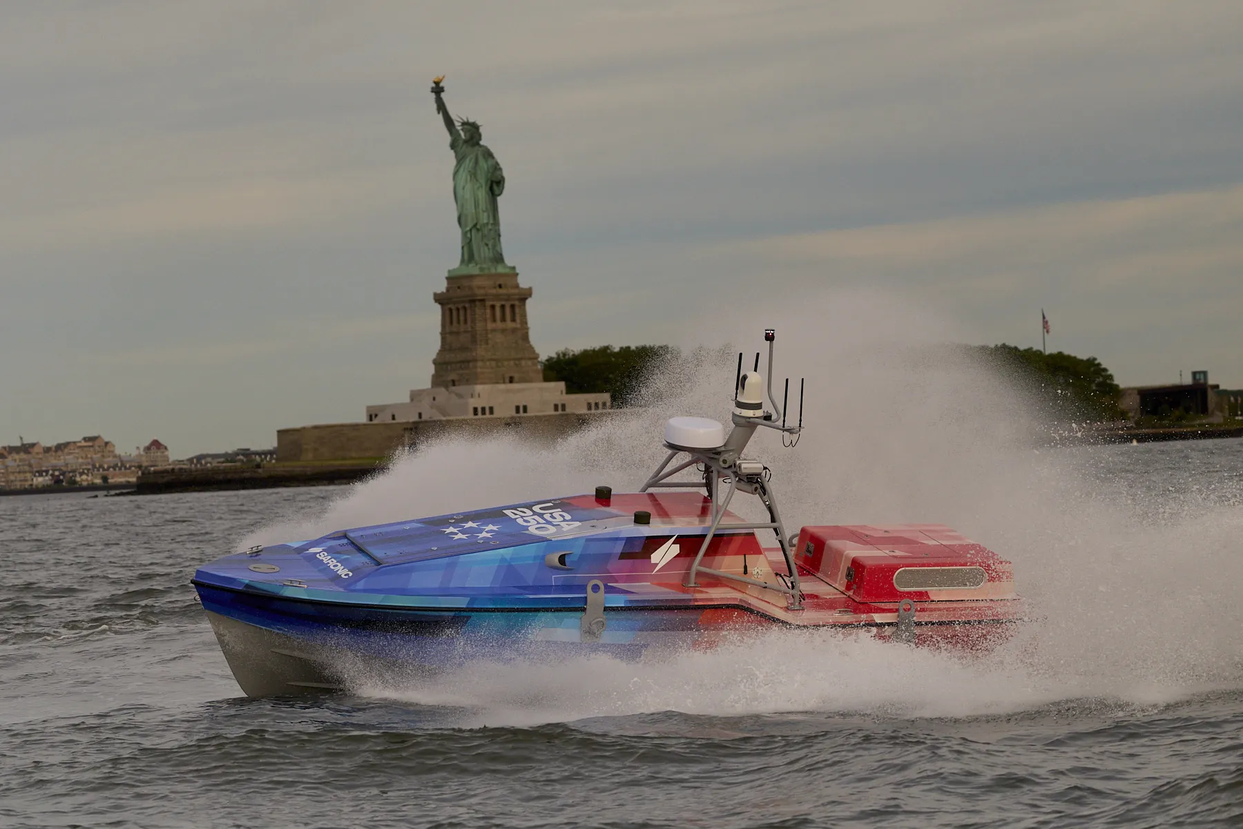 Saronic Corsair vessel patrolling at night near the Statue of Liberty
